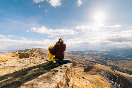 妇女游人与一个大背包坐在高山背景