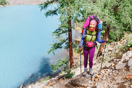 女徒步旅行者站在岩石上, 看着阿尔泰山的湖