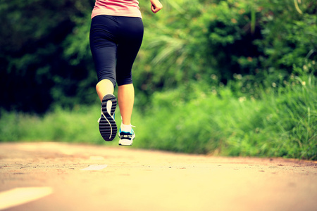 运行在森林步道的年轻健康女性腿部