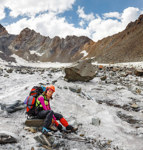 一个妇女冒险家和登山者在一个山通行证附近在冰川在盔甲和与背包