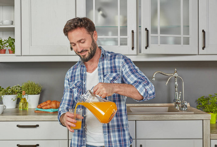 健康男人在厨房里喝橙汁