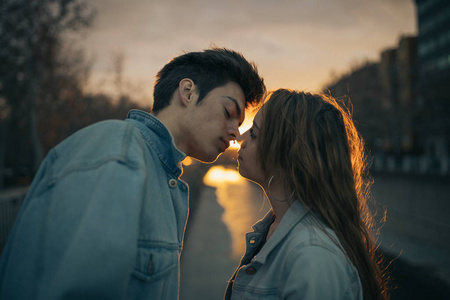 年轻的恋人在美丽的夕阳中接吻。情人节