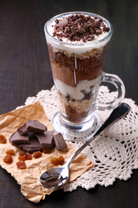 酸奶 奶油夹心巧克力 切碎的巧克力和牛奶什锦早餐服务在玻璃上木制的背景