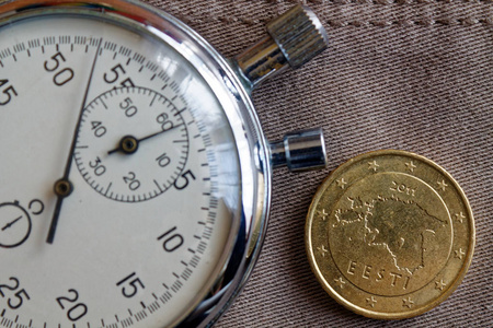 欧元硬币与一个面额的 fifity 欧元美分 背面 和秒表在老米色牛仔裤背景商业背景