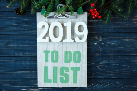 要做的清单上木垫, 白色数字2019和杉木树的分支, 装饰在灰色的木桌。新年目标列表, 事情做圣诞节的概念。平躺与 copysp