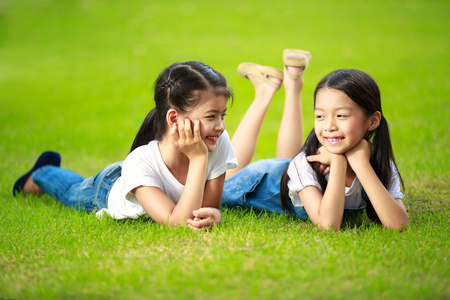 躺在绿草地上的两个小的亚洲女孩