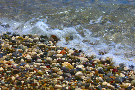 在地中海的海滩上明亮的五颜六色的石头和清澈的海水。焦点贯穿中间