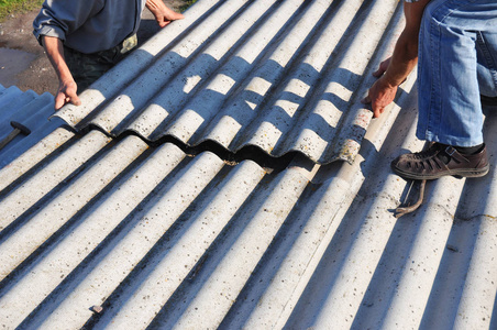 石棉屋面施工。屋顶工安装石棉屋面板