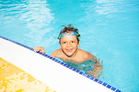 穿着护目镜的快乐男孩的肖像, 在游泳池边休息, 看着相机