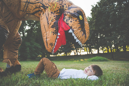 父亲和儿子在公园玩, 与恐龙的服装, 有乐趣与家庭户外