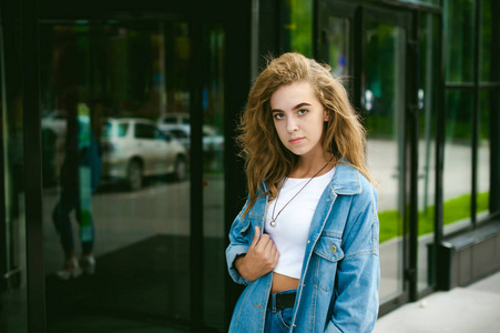 一个年轻的迷人的情感女孩的街头肖像, 穿着时髦的蓝色牛仔西装, 在户外漫步的风格。看摄像机