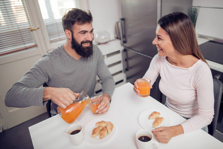 年轻幸福的情侣坐在现代公寓和一起吃早饭