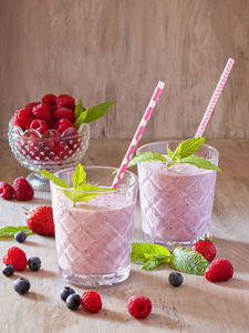 美味的蓝莓, 草莓, 覆盆子和酸奶果汁与浆果和薄荷周围的木质背景