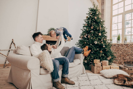 圣诞树上的年轻夫妇的肖像在沙发上的小男孩