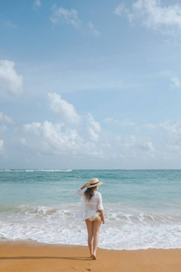 女孩在一顶草帽沿海滩漫步