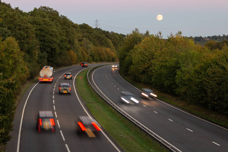 英国双车道道路在日落与上升满月背景