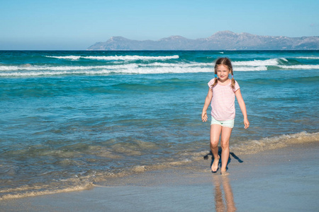 可爱的女孩漫步在海滩上