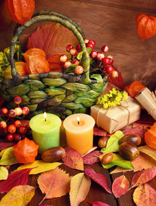 秋天舒适的静物。在木背景的蜡烛, 浆果, 秋叶和酸浆
