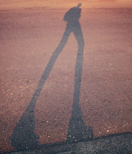 在日出或日落时, 一个人沿着路边走在停车场的长阴影, 带有复古复古的 instagram 过滤器