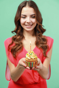 快乐的年轻女子举行生日蛋糕与蜡烛的颜色背景