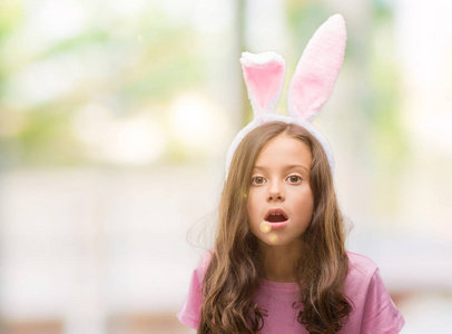 褐发女郎拉美裔女孩穿着复活节兔子耳朵害怕在休克与惊讶的脸, 害怕和兴奋与恐惧表达
