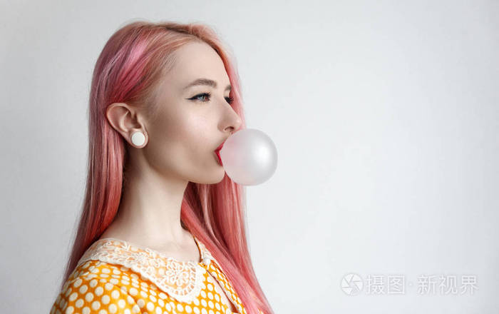 那个粉红色头发的女孩正在吹泡沫口香糖.