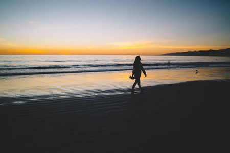 女人的身影漫步在沙滩上, 美丽的金色日落, 在平静的水面上, 孤独的女孩漫步在海边的海岸线上, 望着风景明媚的黎明在夏日重现 v