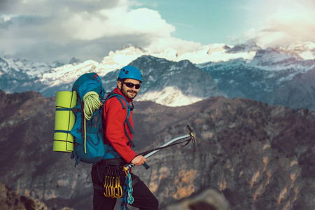 年轻的登山运动员站在山顶上的背包和欣赏的看法