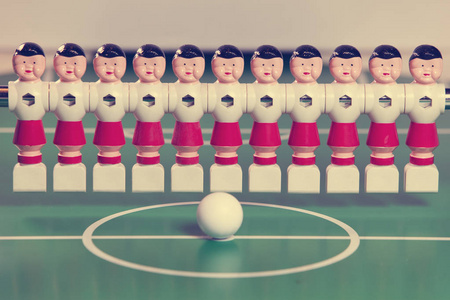 玩具足球运动员站在球场上的一排和一个球在中心, 复古有效
