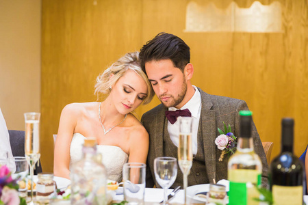 坐在桌边的年轻漂亮的新婚夫妇在餐厅里闭着眼睛