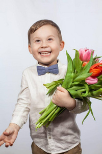 可爱的小男孩捧着一束花。郁金香.母亲节。国际妇女节。一个快乐的小男孩的肖像