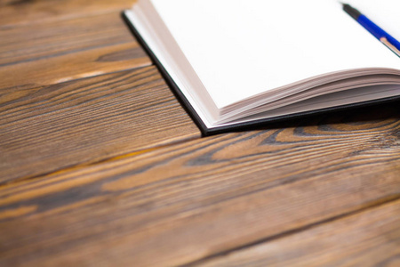 圆珠笔在笔记本上的深棕色木质背景。笔记本中的空白页。无概念写作