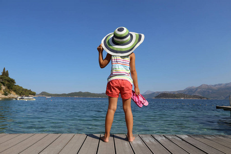 小女孩在大帽子享受海滩和日光浴在海滨度假胜地