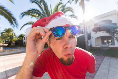笑话, 假日和圣诞节概念年轻滑稽开朗的人在圣帽持有太阳镜