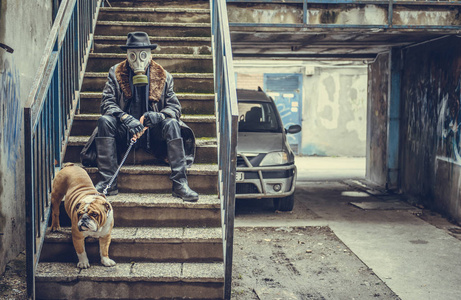 戴防毒面具的男子手持英国斗牛犬, 坐在楼梯上, 选择性对焦