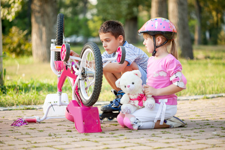小女孩粉红色的安全帽，学会了如何修理自行车