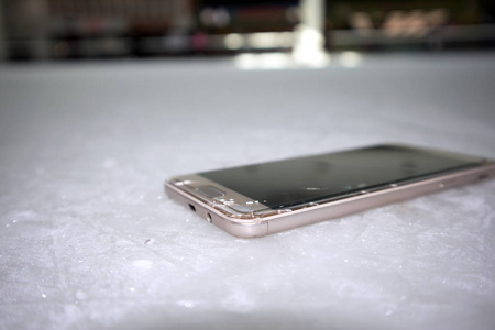 现代智能手机与开裂的屏幕玻璃躺在刮伤的冰