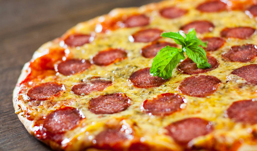 意大利香肠比萨配芝士意大利香肠番茄酱胡椒香料和新鲜罗勒。意大利披萨在木背景