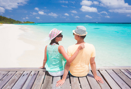 在马尔代夫热带海滩上坐着的情侣的后景色