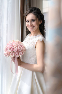 美丽的新娘在窗口与婚礼花束