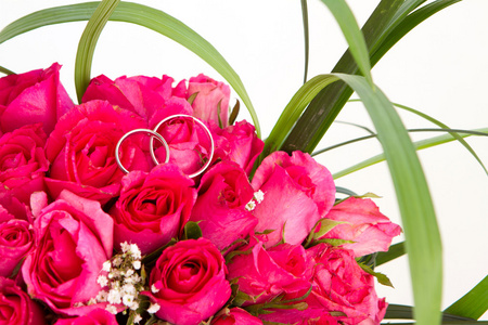 结婚戒指和新娘捧花的分离对 whi 的粉红玫瑰