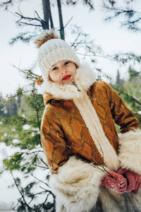 小女孩在冬天礼服在充满雪的森林里