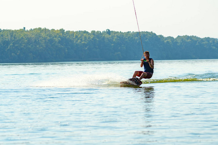 Wakeboarder 在阳光明媚的一天在有线公园的训练中骑得很滑稽。