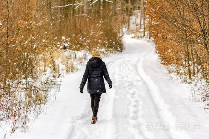 冬天在雪地里散步的女人.女孩在雪的路在森林里