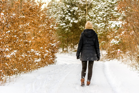 女人走在冬日的雪路上, 女孩穿着暖和的冬衣, 回头看