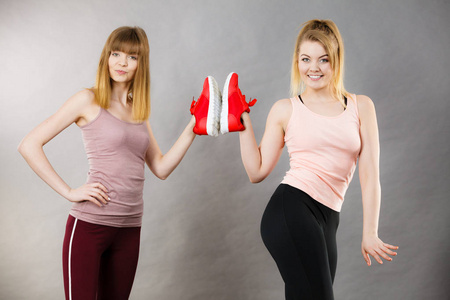 两个快乐运动微笑妇女展示运动服运动鞋红鞋，舒适的鞋子适合锻炼和培训