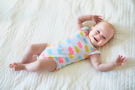 躺在床上微笑的女婴。快乐健康的小孩子笑。婴儿儿童在阳光苗圃