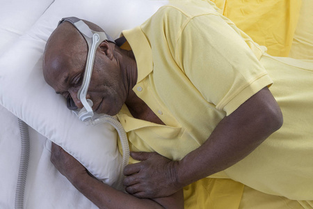 保健概念, 非洲, 美国男子阻塞性睡眠呼吸暂停睡眠良好与 cpap 机, 男子躺在床上穿着 cpap 口罩, 白色背景