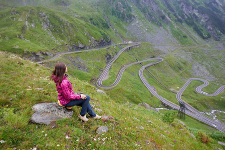 女孩坐在一块石头上, 享受着美妙的山景。Transfagarashan 公路, 欧洲最美丽的道路, 山脊 Fagaras