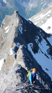 登山者在陡峭和裸露的岩石山脊上, 在他的途中到一个高峰